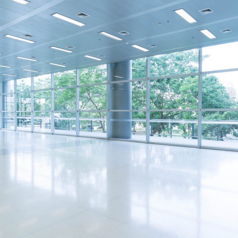 Blurred abstract background interior view looking out toward to empty office lobby and entrance doors and glass curtain wall with frame - blue white balance processing style